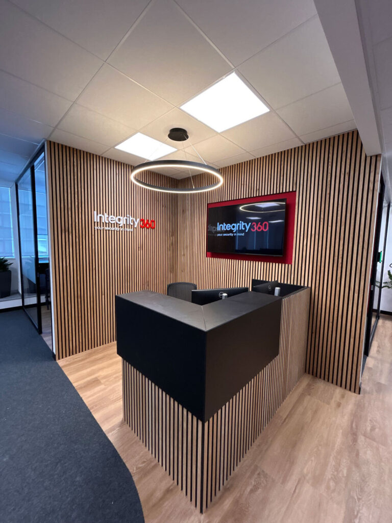 Ufficio Integrity 360 con postazioni operative modulari, reception personalizzata e pareti vetrate per sala meeting