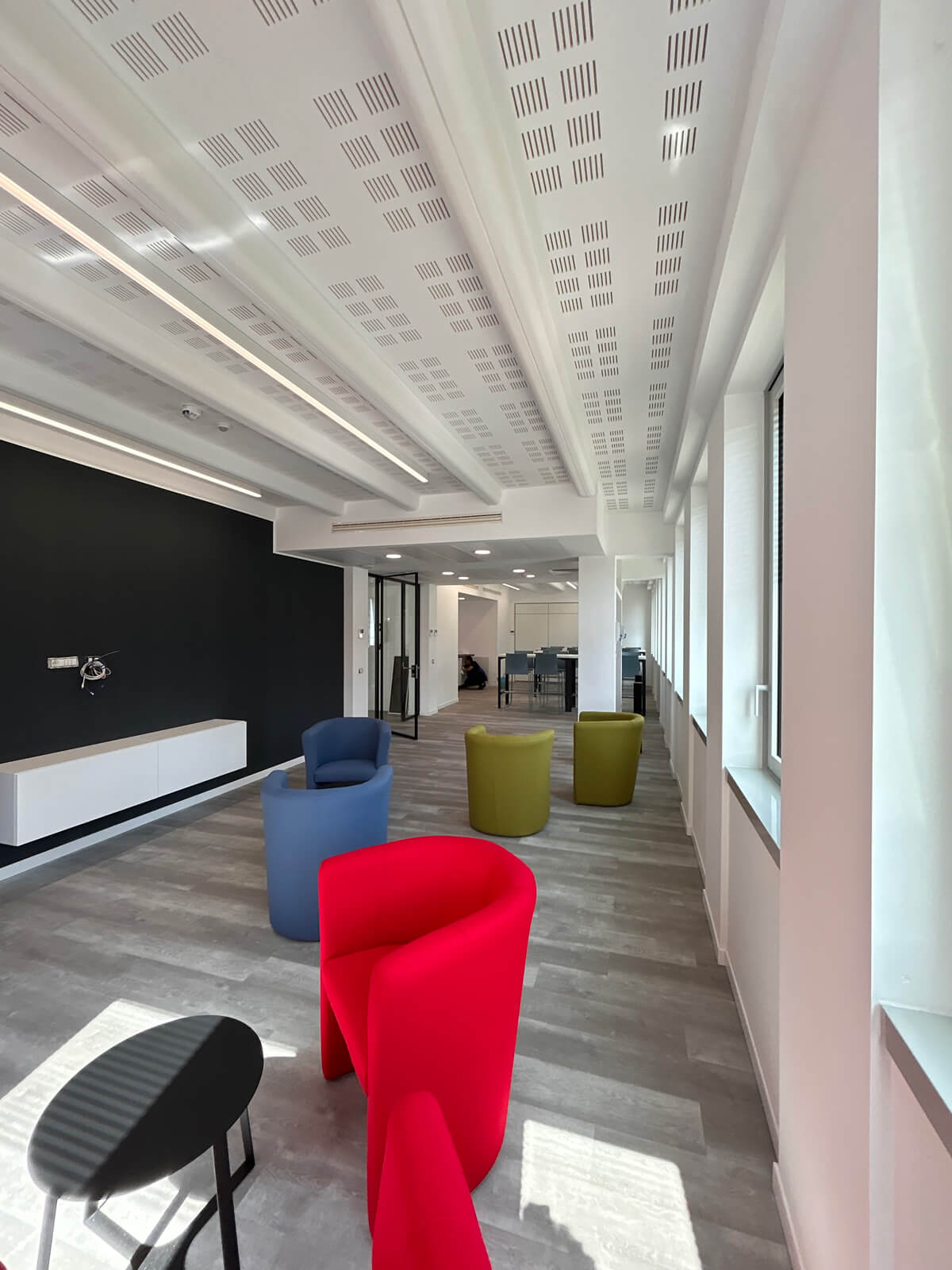 Allestimento ufficio Solco con pareti vetrate, postazioni operative, area lounge e arredi moderni